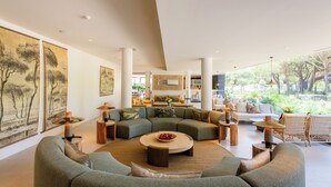 A spacious living area with a large sectional sofa, a round coffee table, and a dining area with a wooden table and chairs.