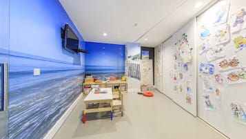 Children can play and create in this imaginative space with a vibrant ocean mural, a small table for activities, a whiteboard for art, and a TV for entertainment.