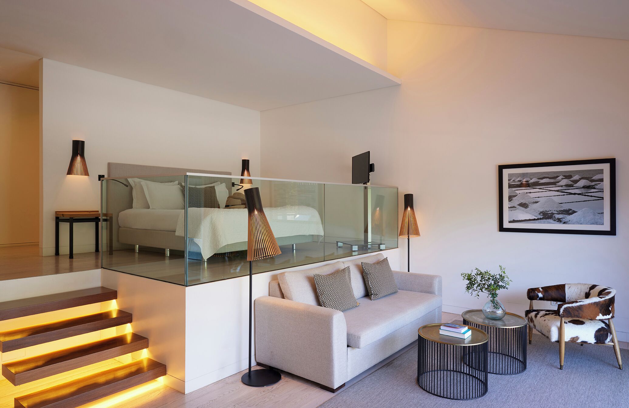A modern living room with a glass partition, a sofa, a coffee table, and a chair.