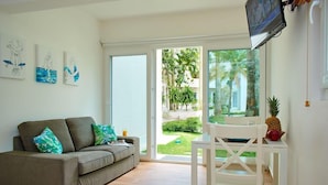 Ein Wohnzimmer mit grauem Sofa, einem weißen Tisch und einem an der Wand befestigten Fernseher.