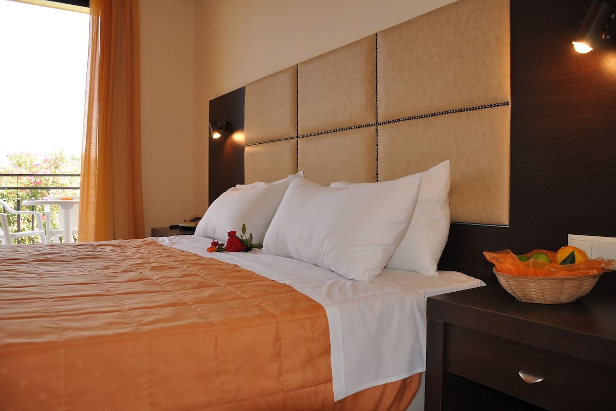 Habitación de hotel con una cama grande, una mesita de noche y una cesta de mimbre con fruta.