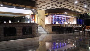 A bar area with a curved counter, seating, and a staircase leading to an upper level. - Pegasus Hotel (Corfu)