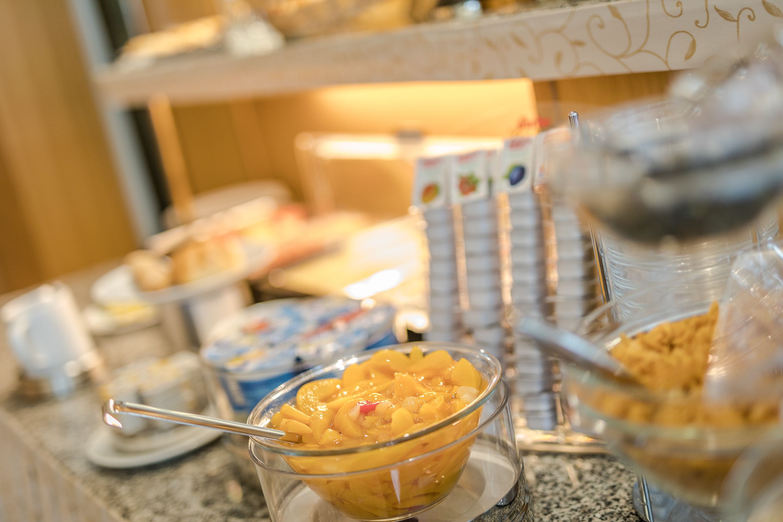 A buffet with various food items including a bowl of fruit salad and other dishes.