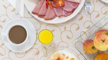 A breakfast setting with a plate of food, a cup of coffee, a glass of orange juice, and a bowl of yogurt with fruit.