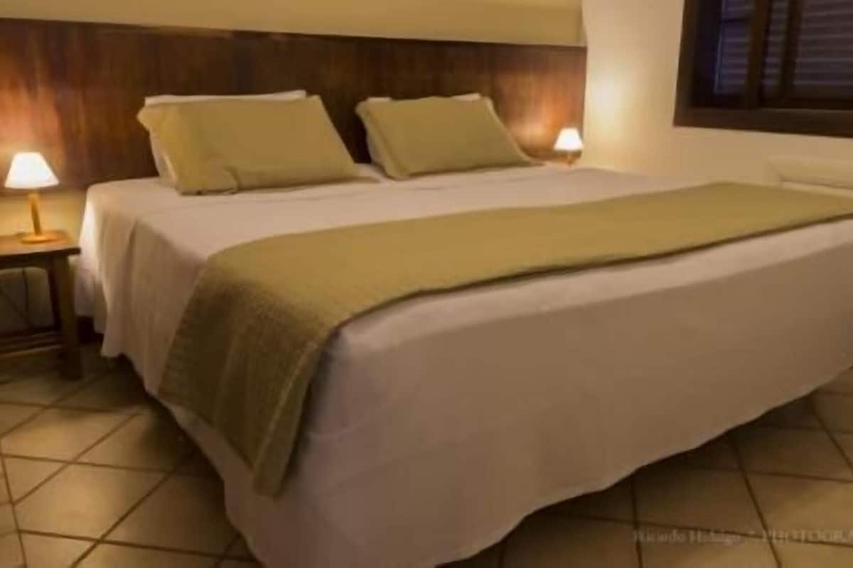 Hotellihuone, jossa on sänky, kaksi yöpöytää ja ikkuna.