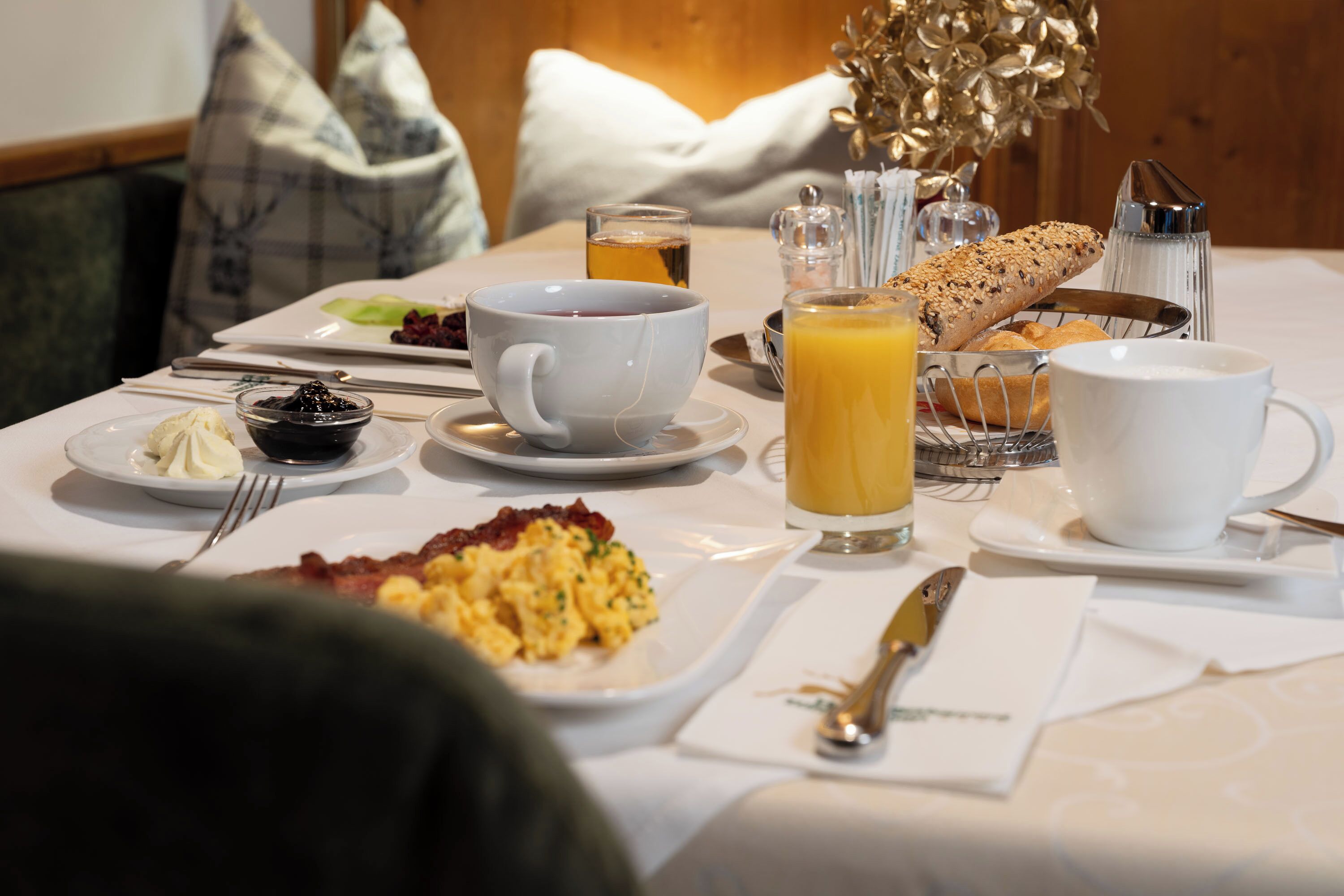 Una mesa de desayuno con huevos revueltos, tostadas, jugo y café.