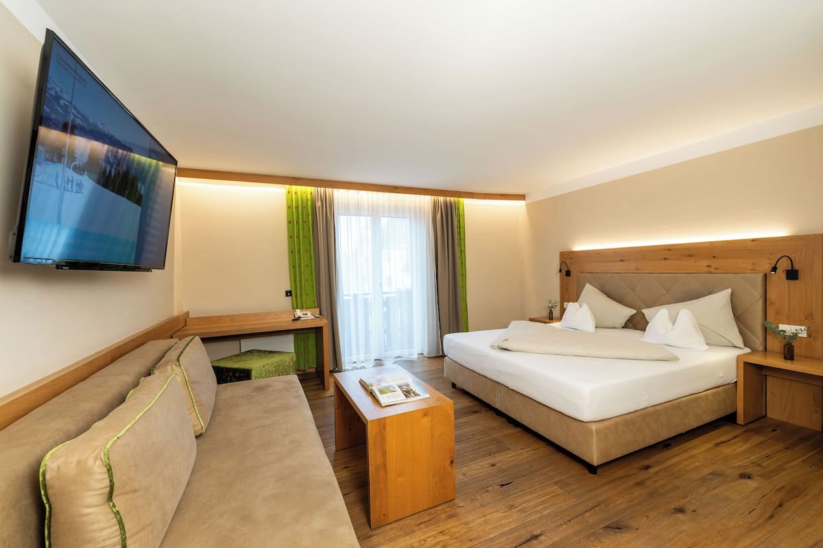 Een hotelkamer met een bed, een bank, een televisie en een bureau.