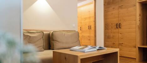 A modern room with a wooden floor, a beige sofa, a wooden table, and a wardrobe with two doors.