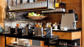 Un bar à petit-déjeuner équipé de machines à café, d’un panier de fruits et d’une variété de verres.