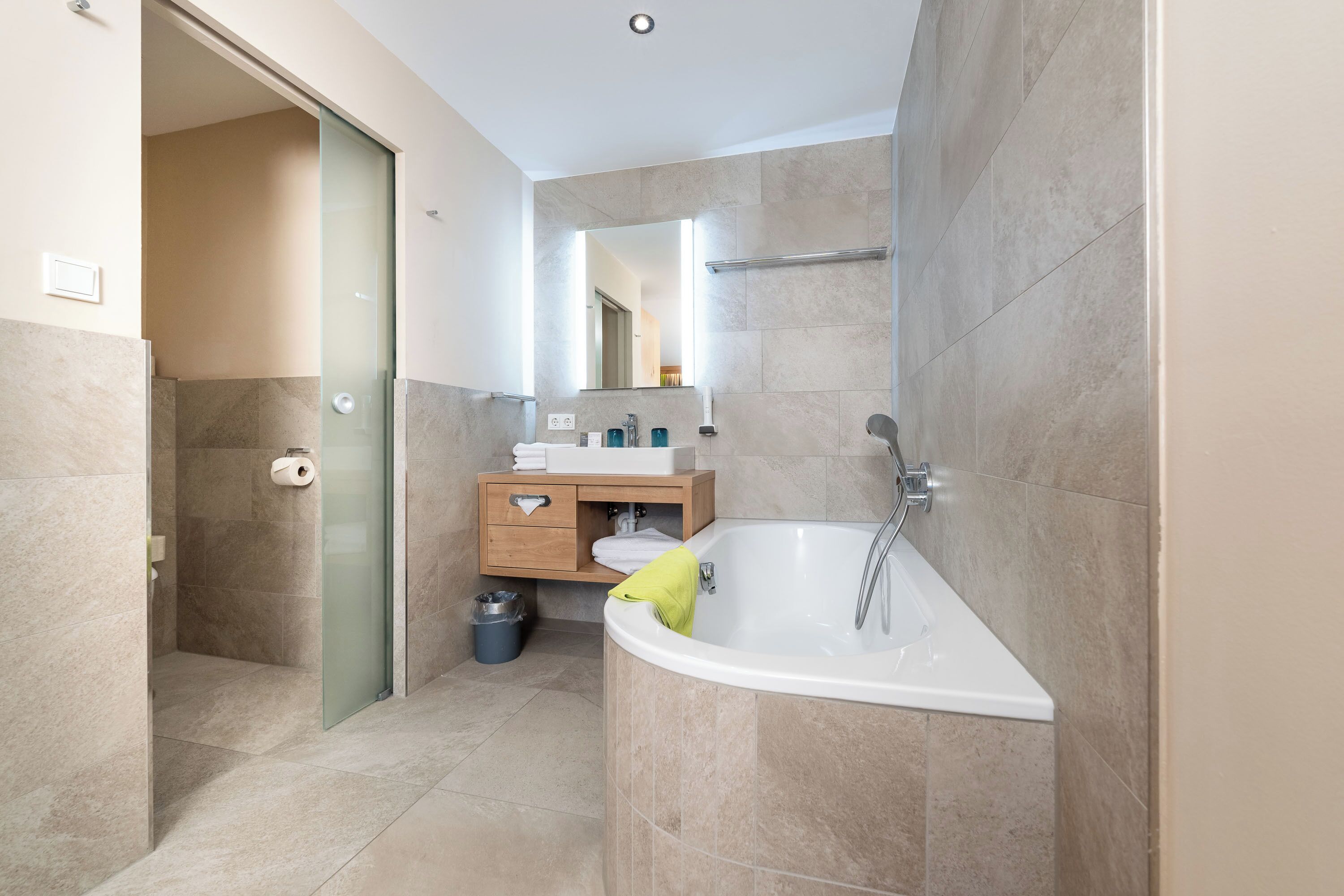 A modern bathroom with a glass shower enclosure, a built-in sink, and a vanity with a mirror.