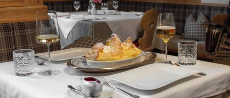 A dining table set with plates, glasses, and a dessert dish.