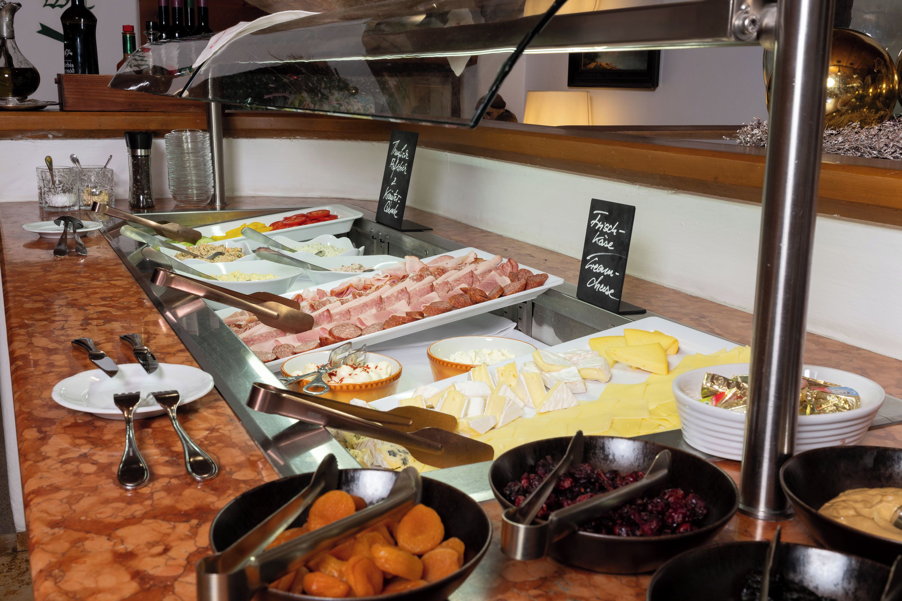 A buffet with various food items including meats, cheeses, and fruits.
