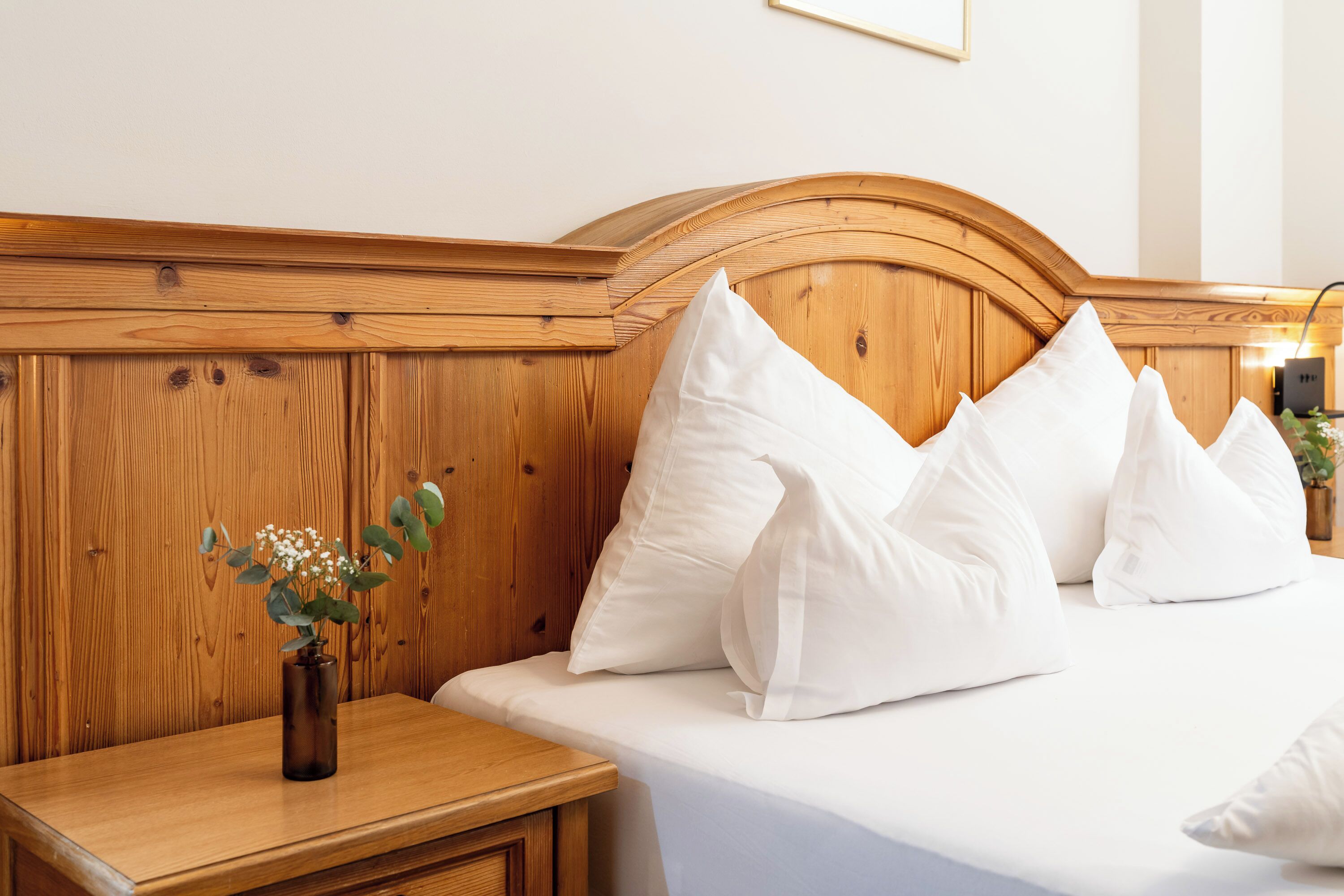 A neatly made bed with white pillows and a wooden headboard.
