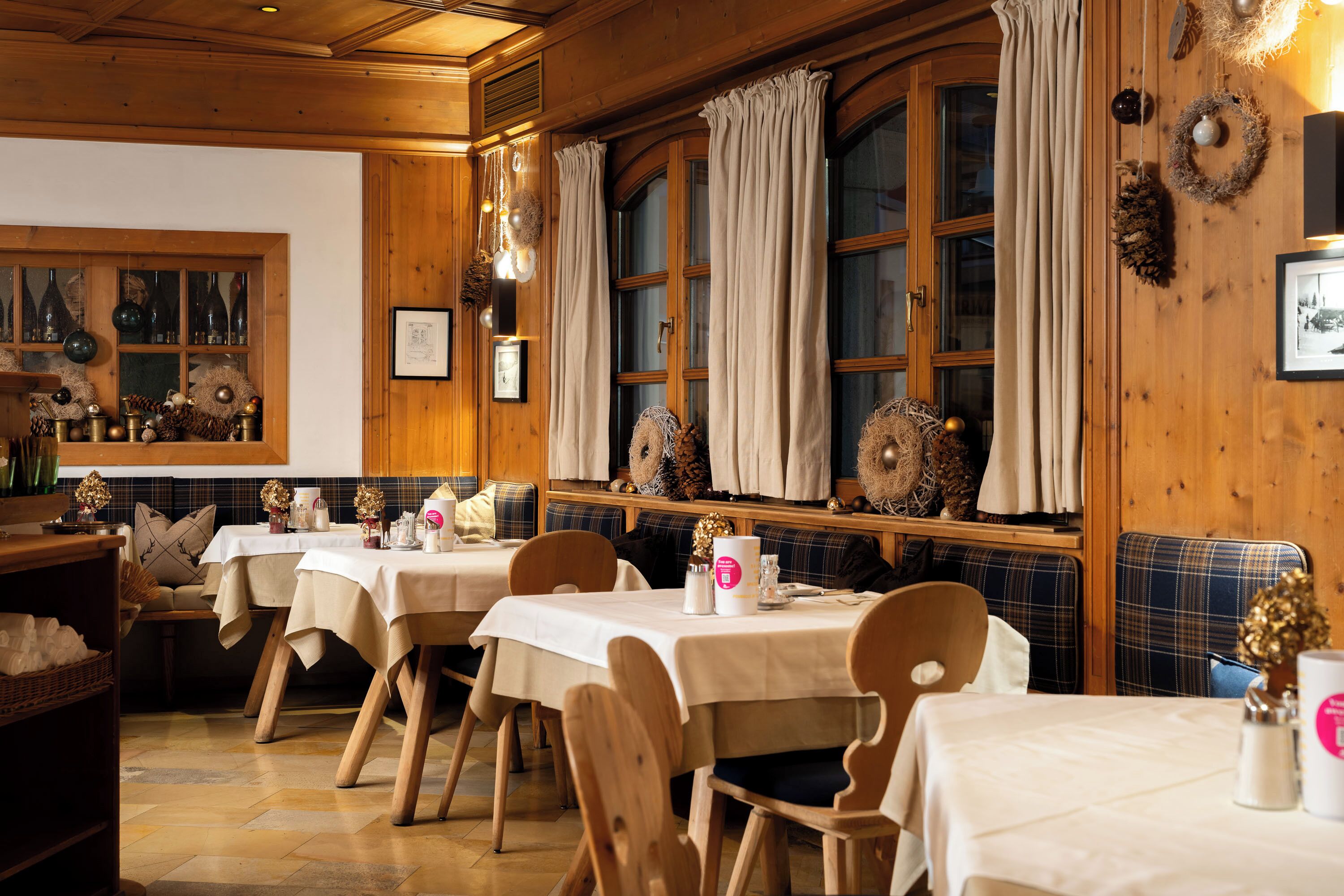 Un restaurant accueillant, avec un décor intérieur en bois, de nombreuses tables recouvertes de nappes blanches et une atmosphère chaleureuse.