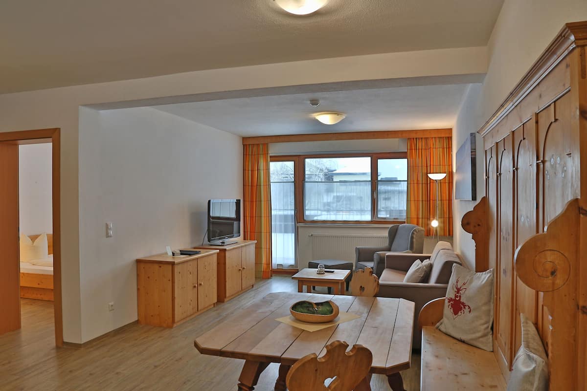 A compact living space with a dining table, wooden cabinets, a television, and a sofa.
