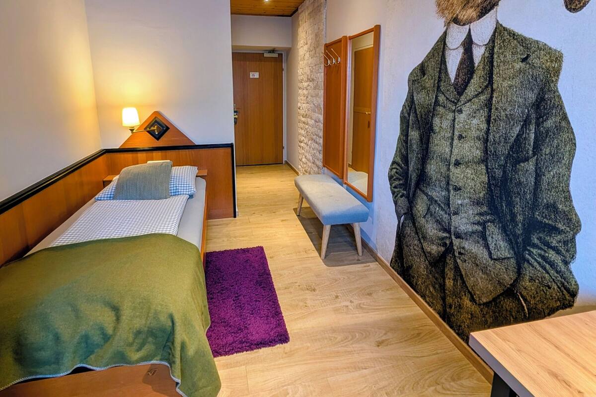Un dormitorio con cama, una banca, un mural en la pared y techo de madera.