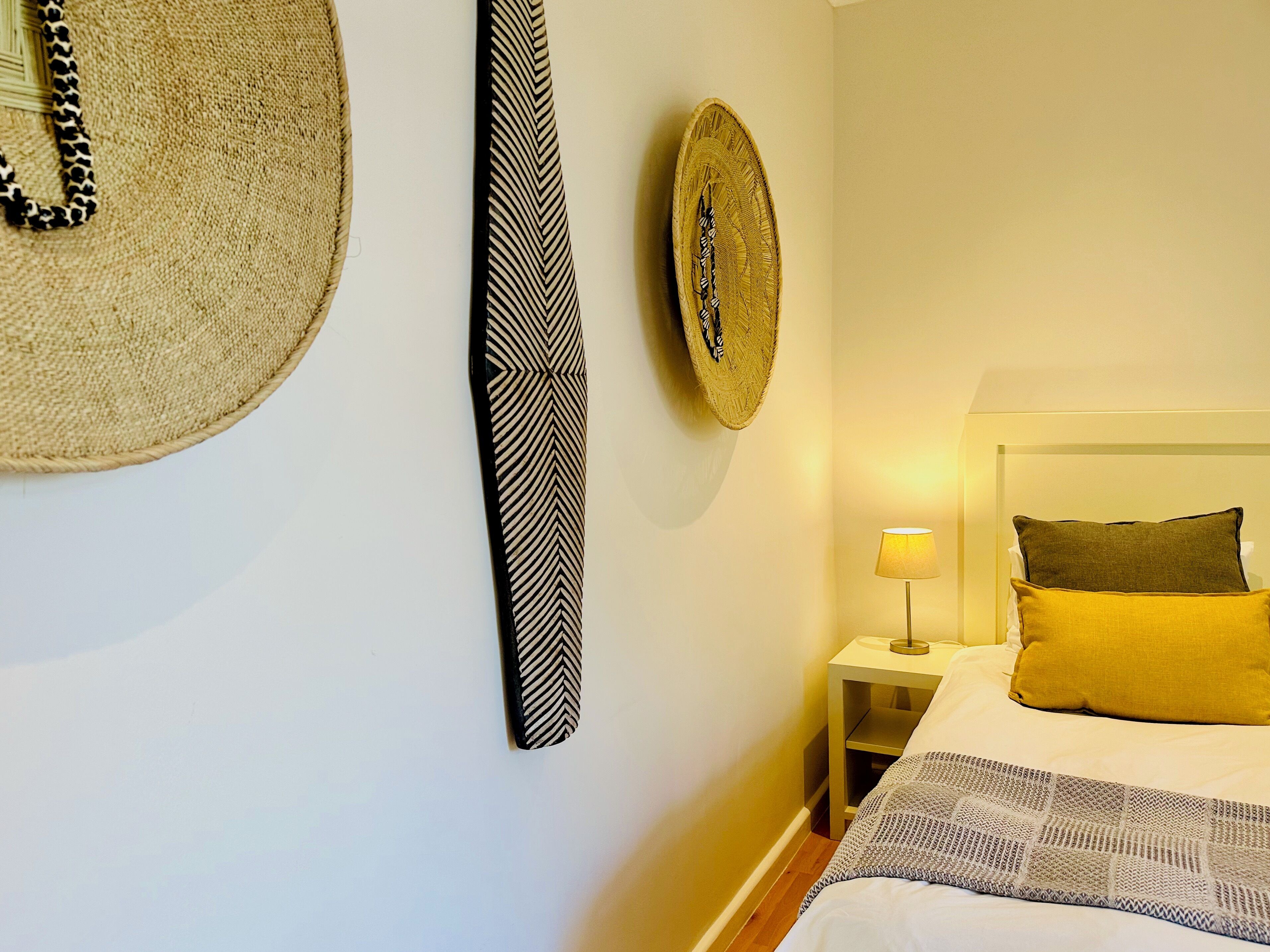 Un dormitorio con cama, mesita de noche, lámpara y adornos en la pared.