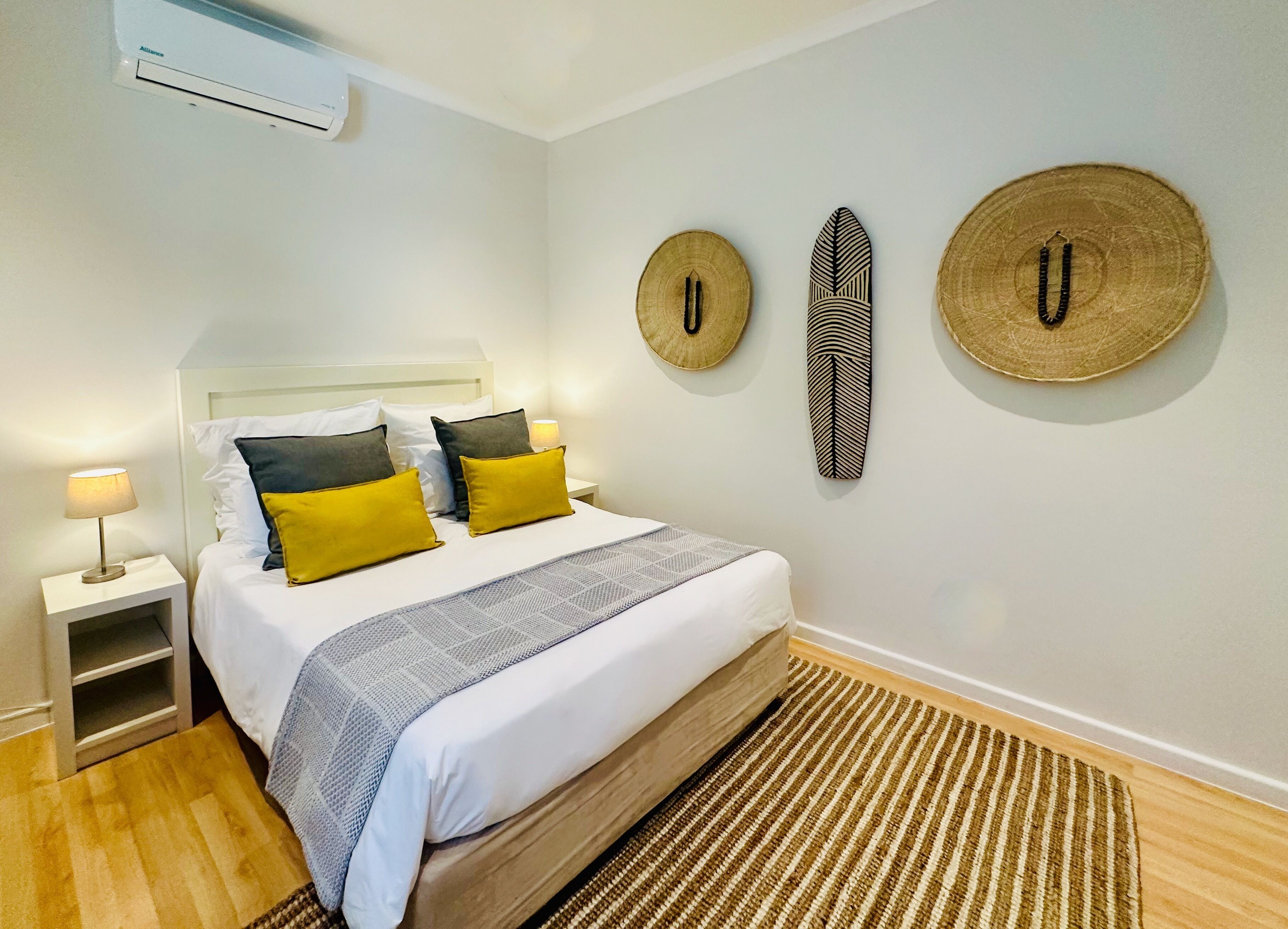 A neatly arranged bedroom with a bed, bedside tables, and wall decor.
