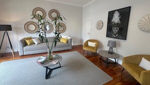 A modern living room with a grey sofa, yellow cushions, a round coffee table, and a large plant. - Loloho Lodge (Cape Town)