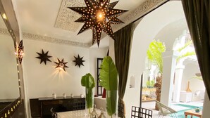 A dining area with a table, chairs, and decorative star-shaped lights. - Riad Fabiola et Spa By La Siredrah (Marrakech)