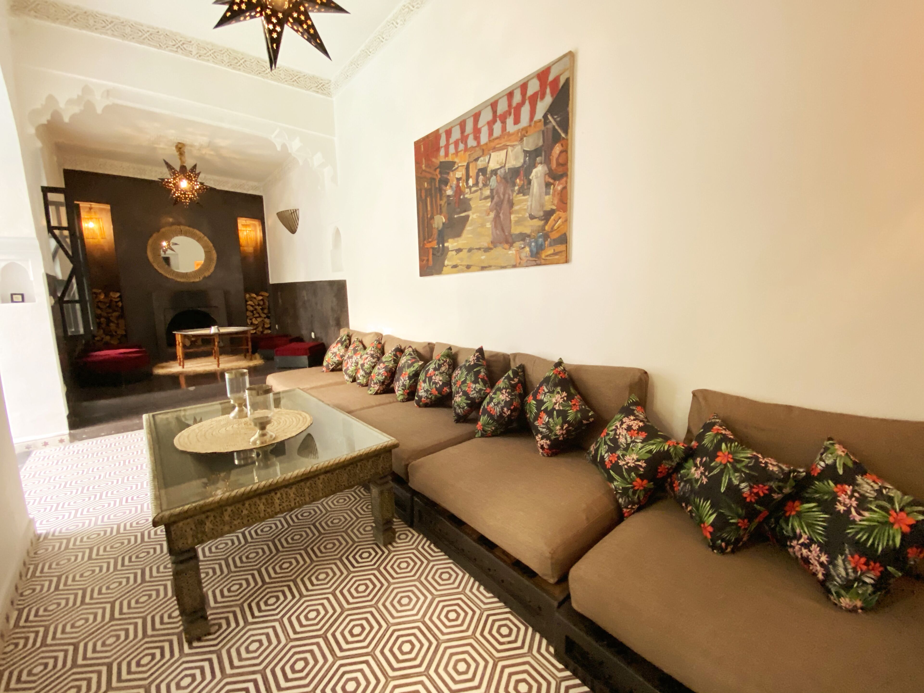 A living room with a sofa, patterned floor, a glass coffee table, a painting, and a fireplace.