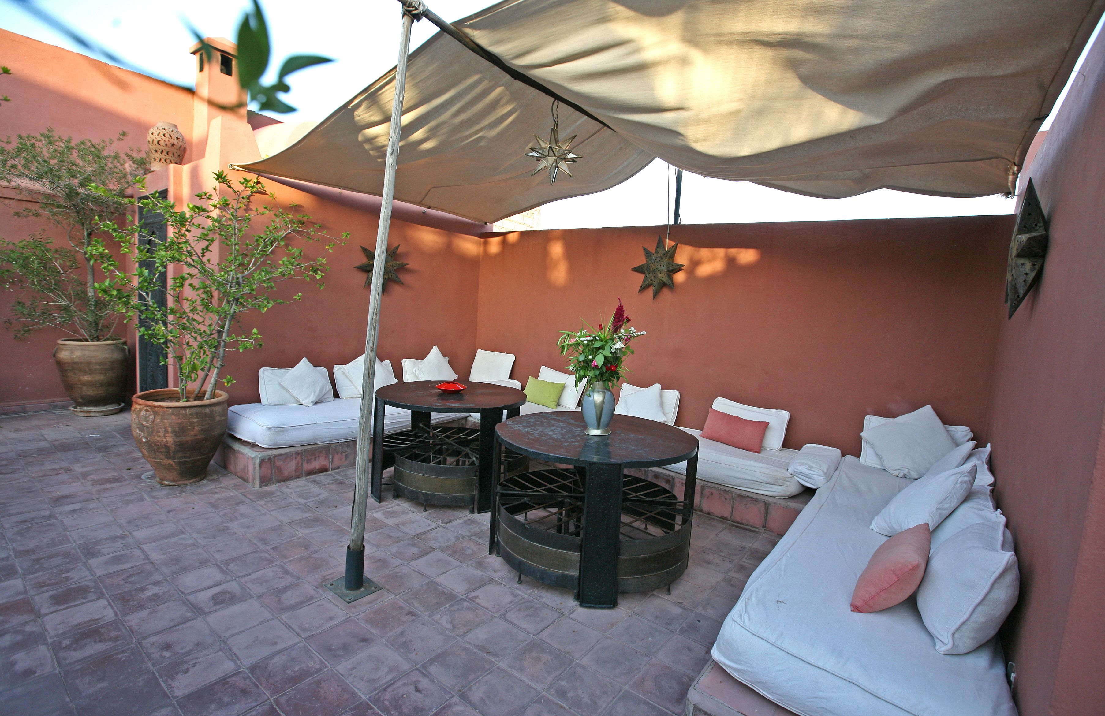 A patio with a sofa, two round tables, and a potted plant.