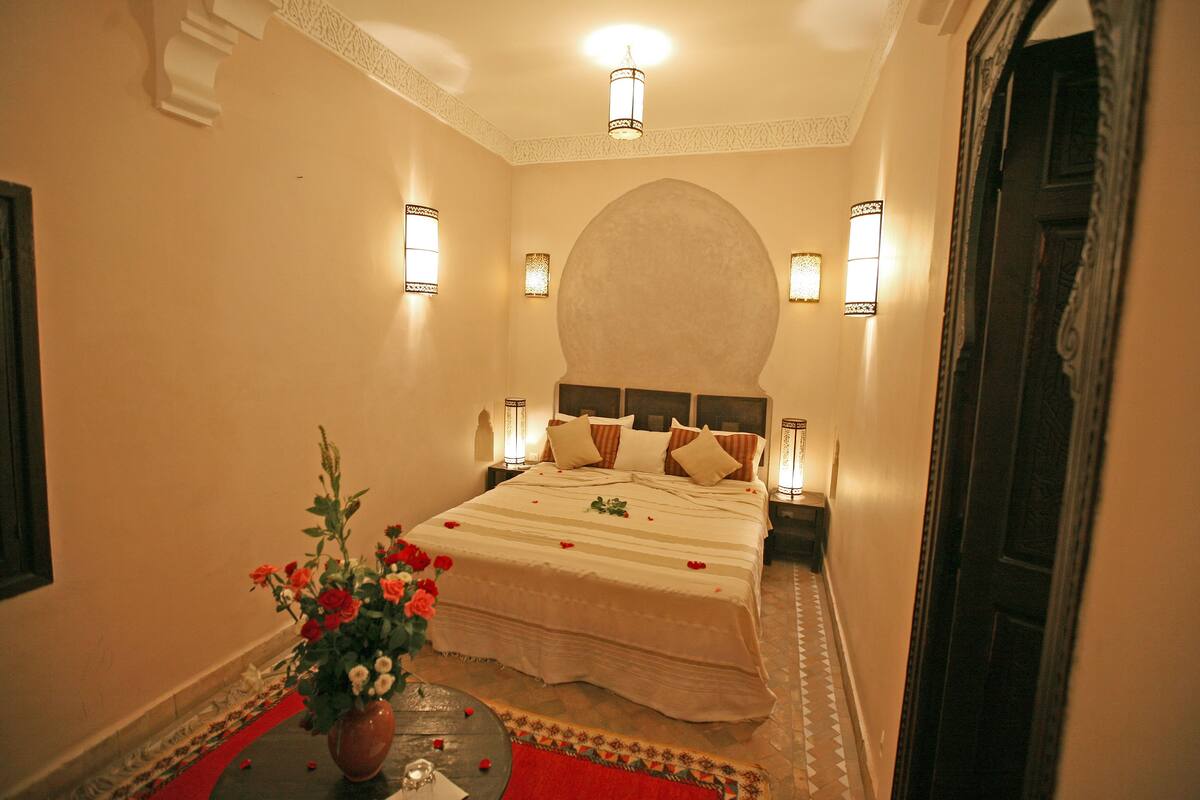 Una habitación de hotel con cama, un florero y apliques decorativos.