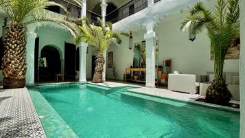 Una piscina al aire libre, sombrillas, sillones reclinables de piscina