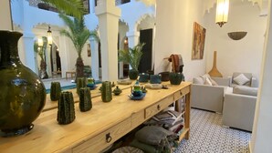 A room with a wooden table, decorative vases, and a patterned floor. - Riad Fabiola et Spa By La Siredrah (Marrakech)