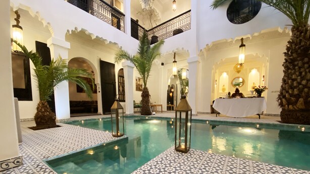 A pool area with tiled flooring, palm trees, and lanterns. - Riad Fabiola et Spa By La Siredrah (Marrakech)