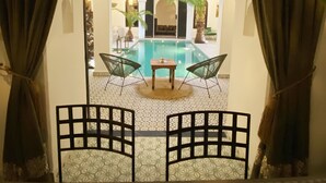 A pool area with a table and chairs, surrounded by a patterned floor and arches. - Riad Fabiola et Spa By La Siredrah (Marrakech)