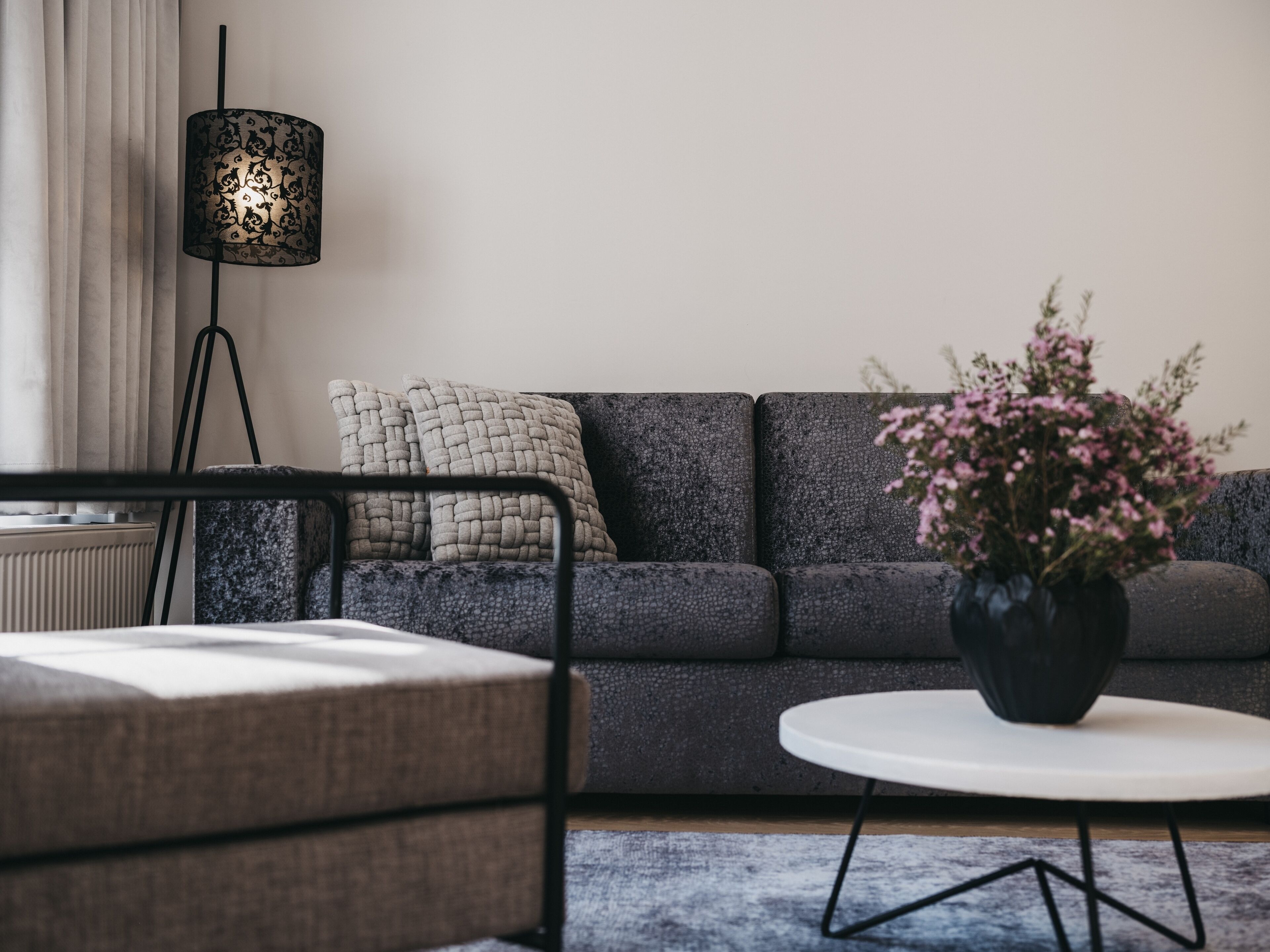 A modern living room with a grey sofa, a white coffee table, and a black floor lamp.