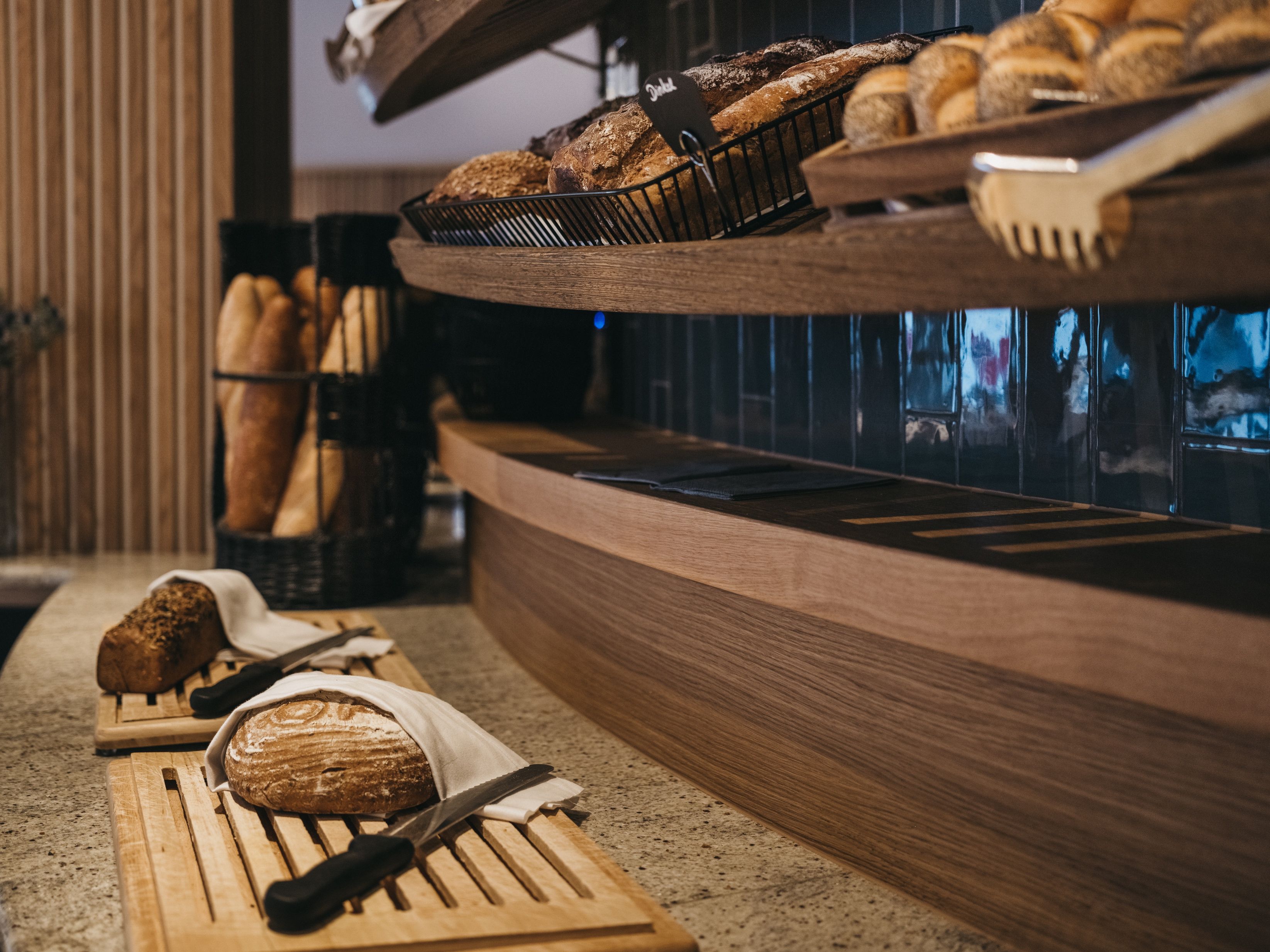 Mostrador de panadería con panes y pasteles varios, un cuchillo y una tabla de cortar.
