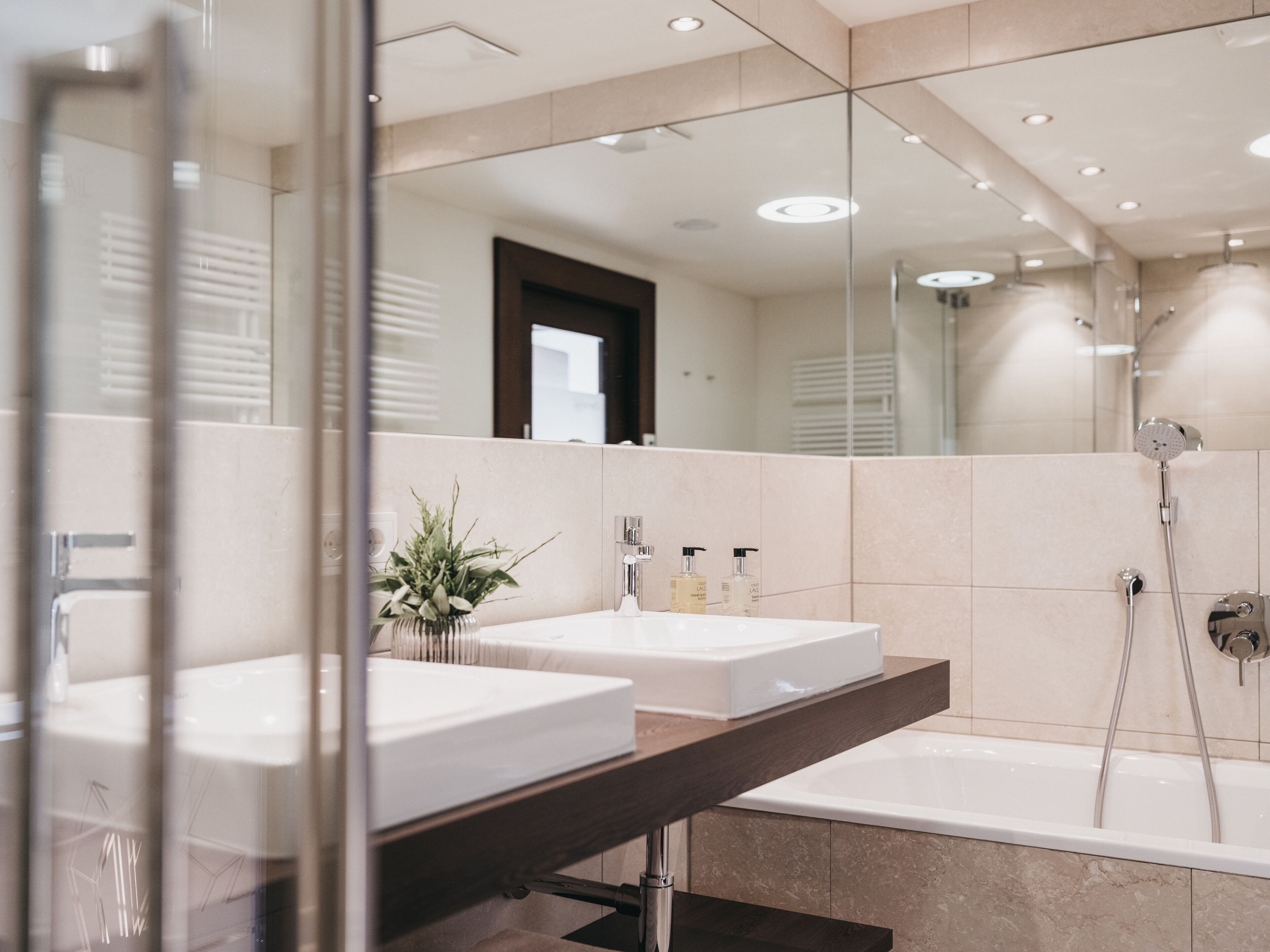 Une salle de bain moderne avec deux lavabos, un grand miroir et une baignoire.