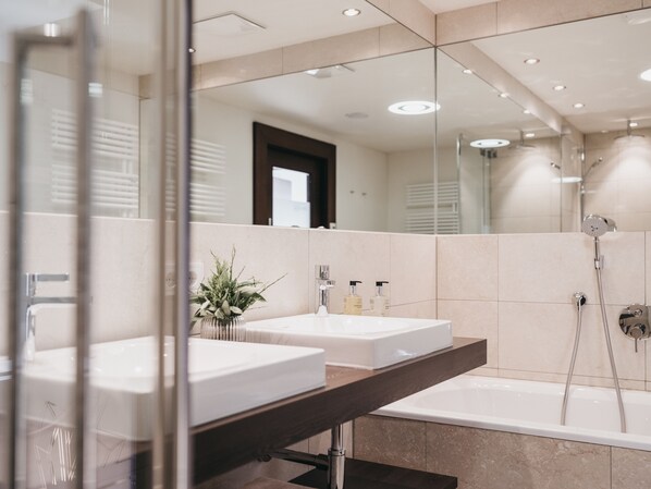 Un baño moderno con dos lavamanos, un espejo grande y una bañera.