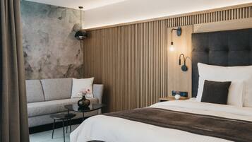 Ein modernes Hotelzimmer mit einem großen Bett, einer Couch, einem kleinen Tisch und einer Wand mit vertikalen Holzlatten.