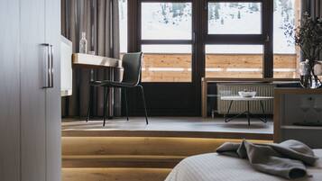 Ein Schlafzimmer mit Bett, Schreibtisch und Stuhl. Ein Fenster bietet Blick auf eine verschneite Landschaft.