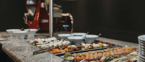 A buffet with various food items including sushi, fruits, and vegetables.