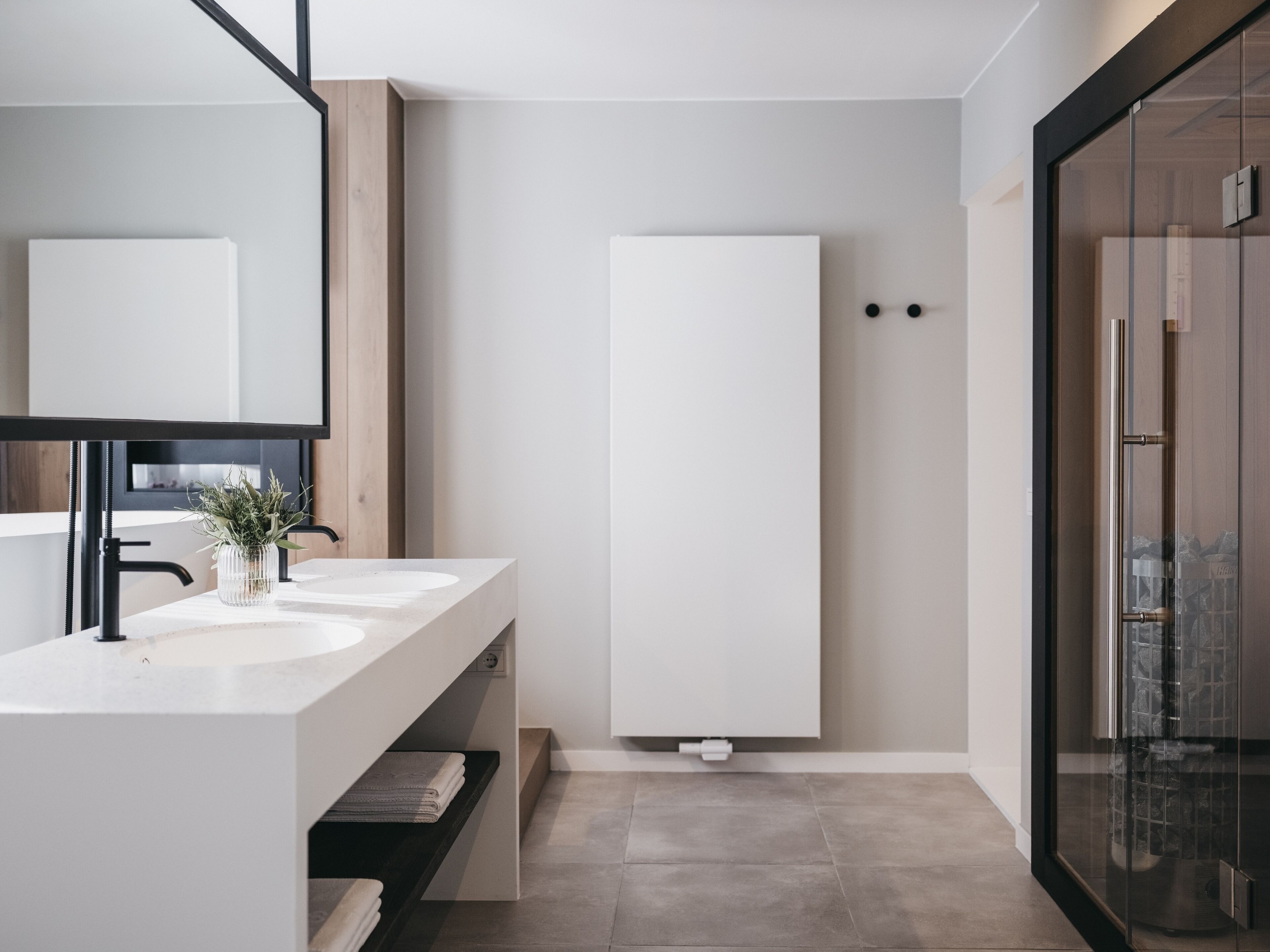 A modern bathroom with two sinks, a large mirror, and a glass shower enclosure.