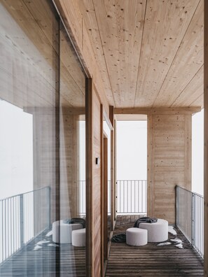 A modern interior with wooden beams, glass walls, and circular seating. - The Crystal VAYA Unique (Obergurgl)