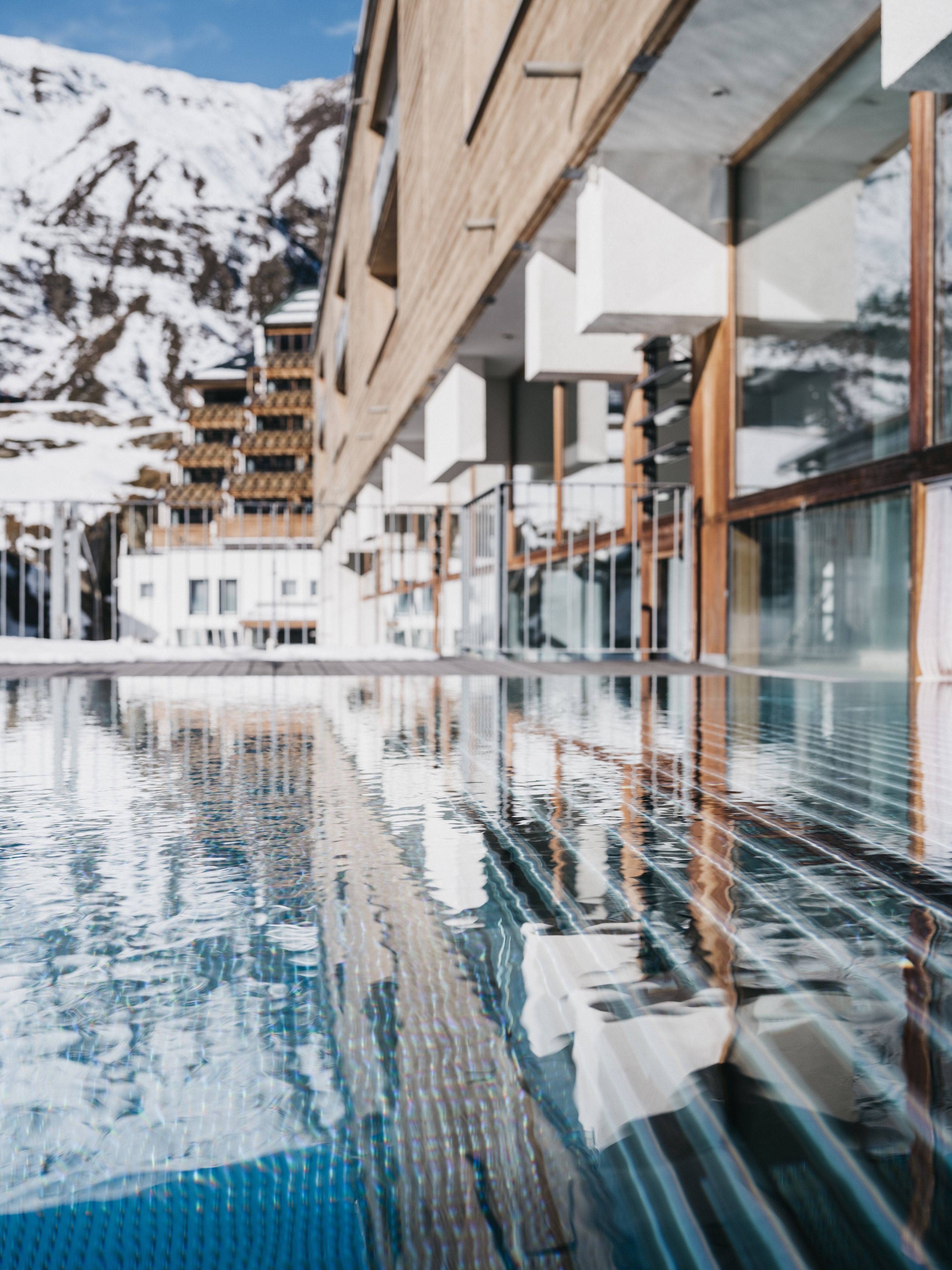 A swimming pool with a clear view of a building and mountains in the background.