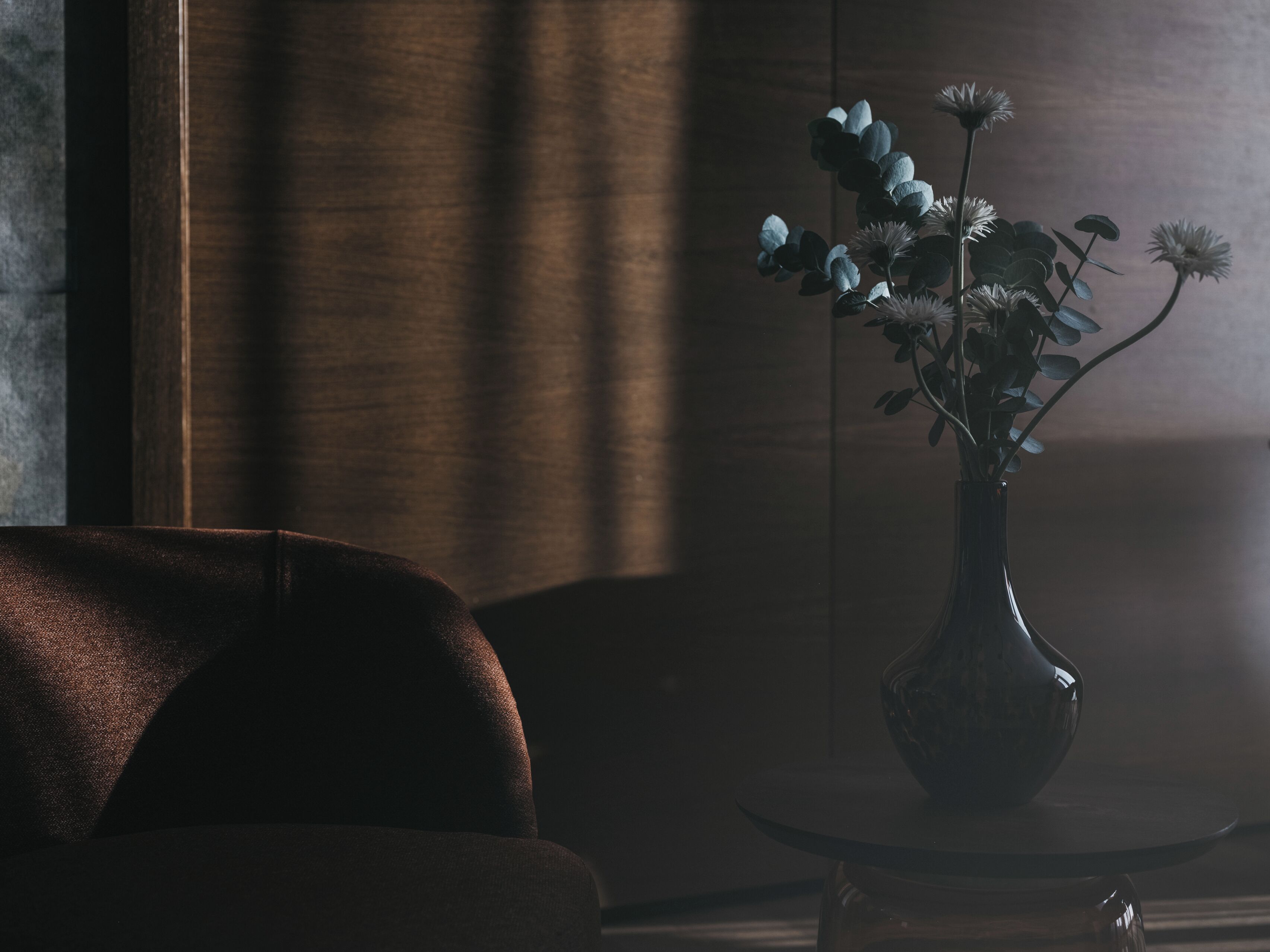 A dark room with a vase of flowers on a table.