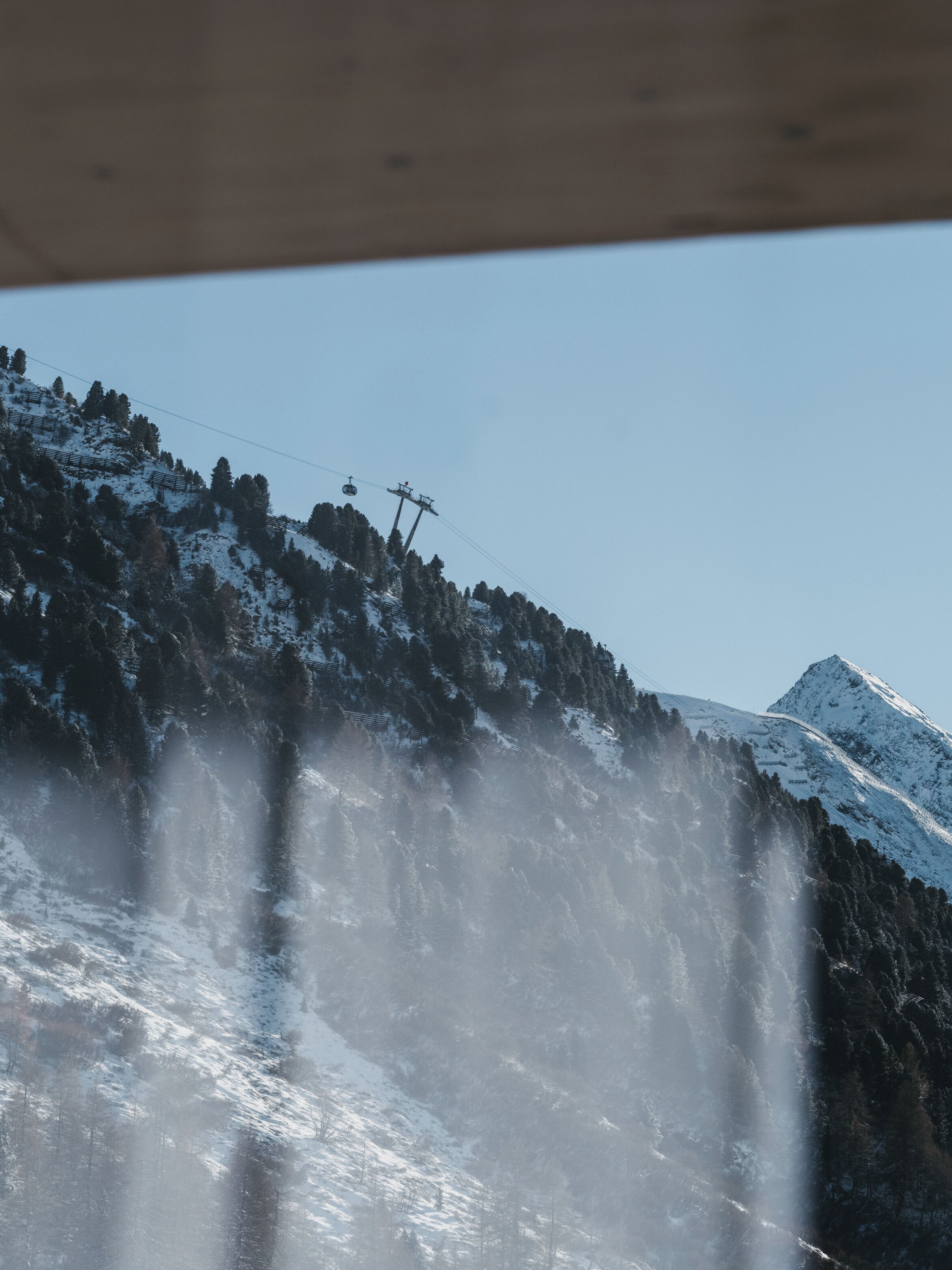 A snowy mountain landscape with a waterfall and a cable car system.