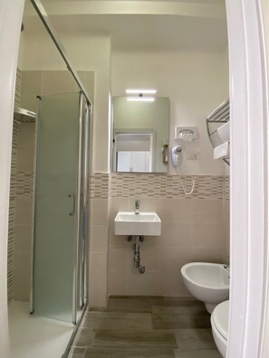 Un baño con cabina de ducha de vidrio, lavabo e inodoro.