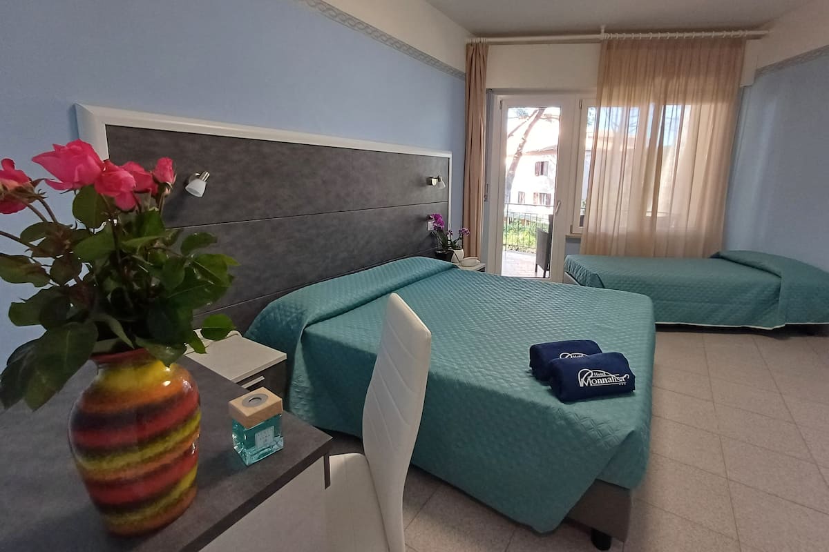 Une chambre d’hôtel avec deux lits, un bureau agrémenté d’un vase de fleurs et une vue sur l’extérieur.