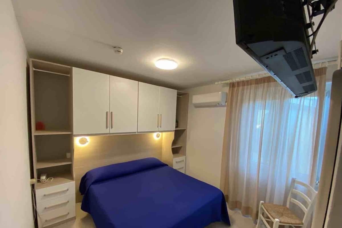 Une chambre à coucher comprenant un lit, un bureau, une chaise et une armoire.
