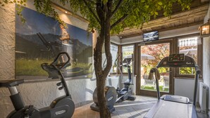 Un gimnasio con bicicletas estáticas, cintas de correr y un árbol.