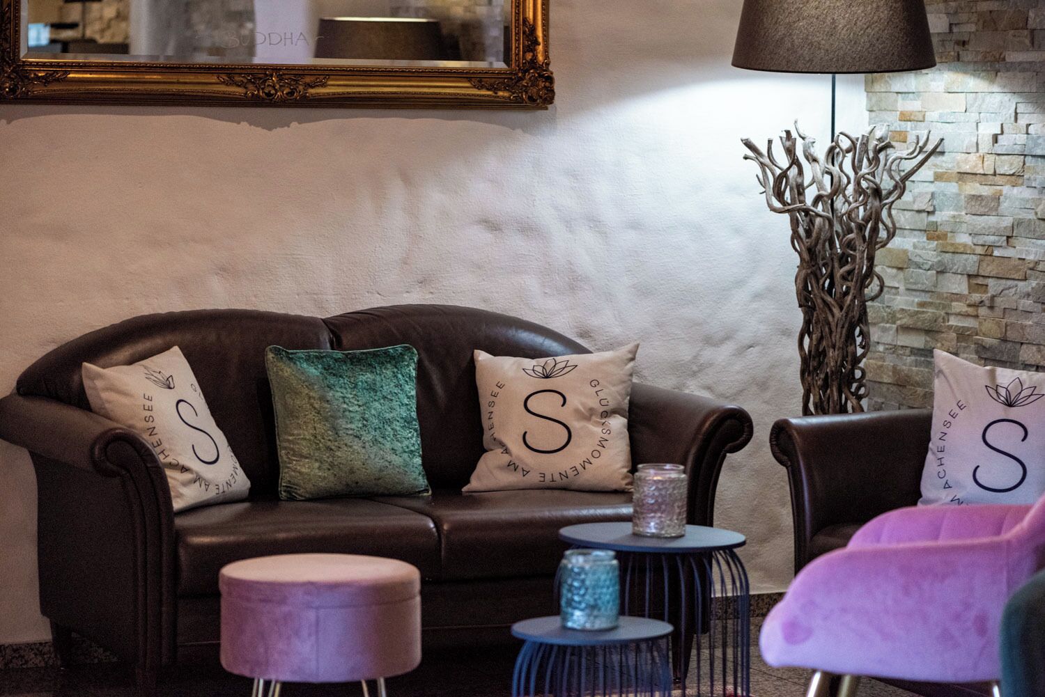 Una zona de estar acogedora con un sofá de cuero, dos mesitas redondas y almohadones decorativos con un monograma.