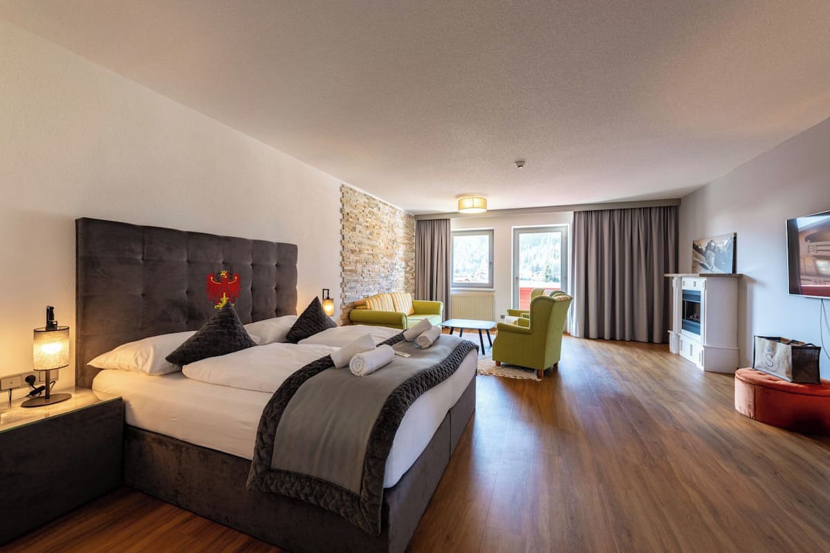 Una habitación de hotel moderna con una cama grande, un pequeño sofá, un televisor y una chimenea.