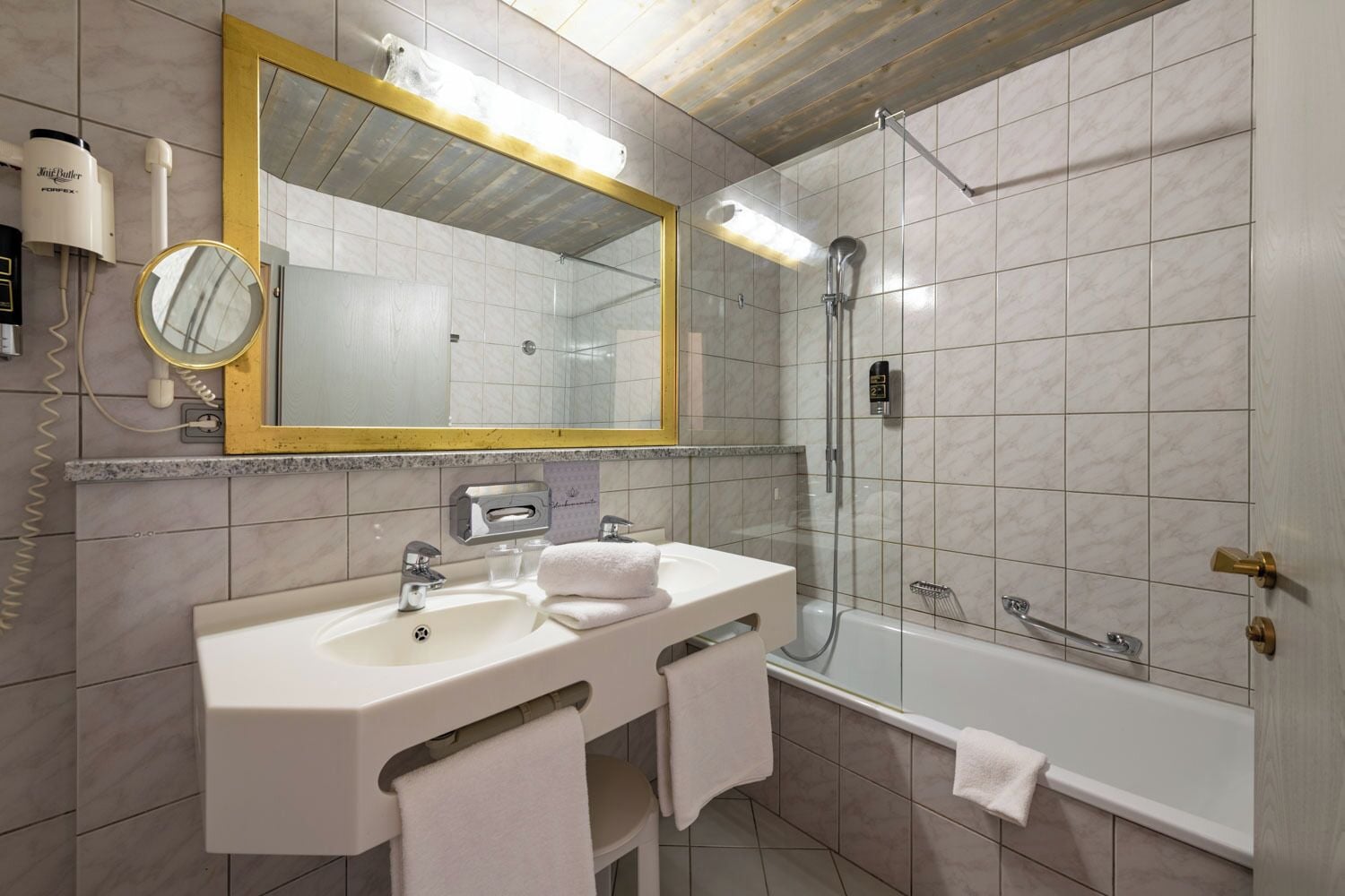 Ein Badezimmer mit Waschbecken, Spiegel, Handtuchhalter, Dusche und Badewanne.